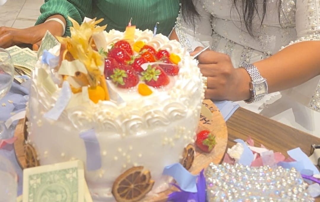 Fruit-topped celebration cake with guests gathered around